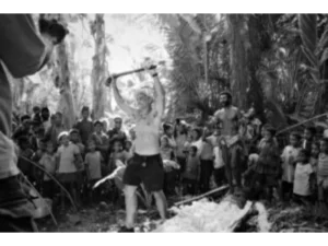 A tourist lifting up the sago beating tool after beating the sago with it at Bwabwasai village, Sanaroa Island