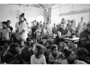 First tourists on Sanaroa Island sitting on desks inside the local school classroom